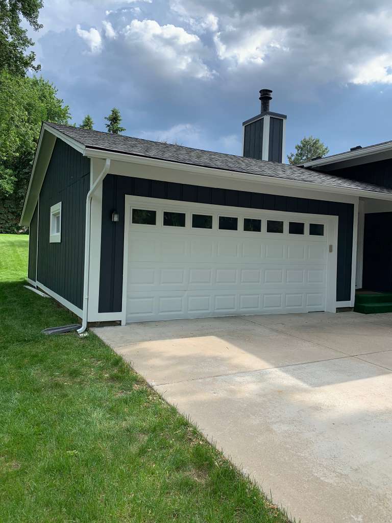 Modern home painted navy blue with white garage
